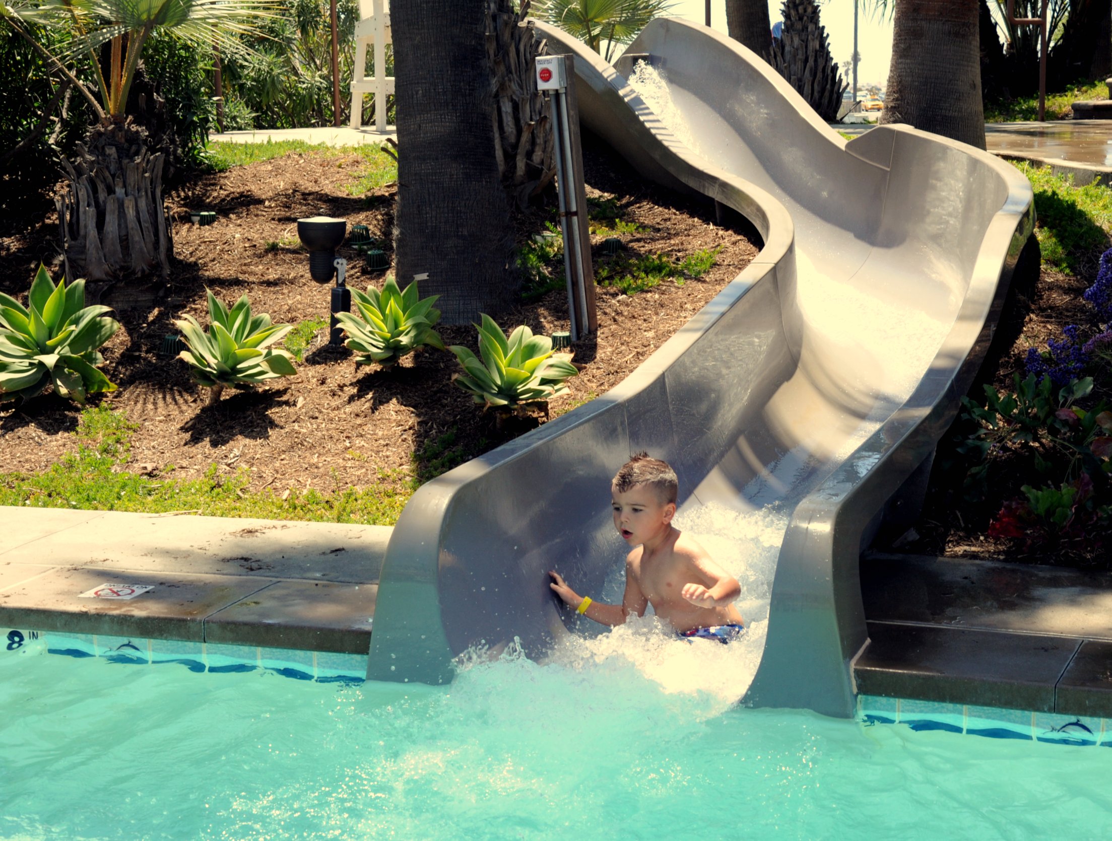 a small child plays on a slide at a resort pool