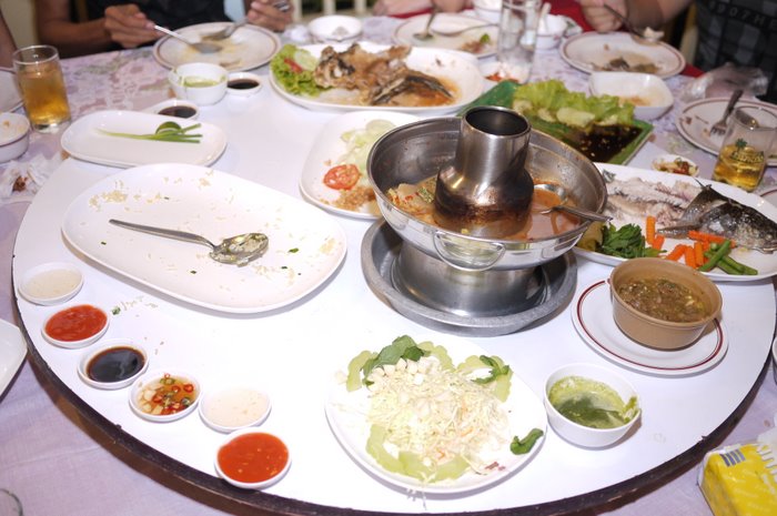 several people are sitting around a white round table with food in it