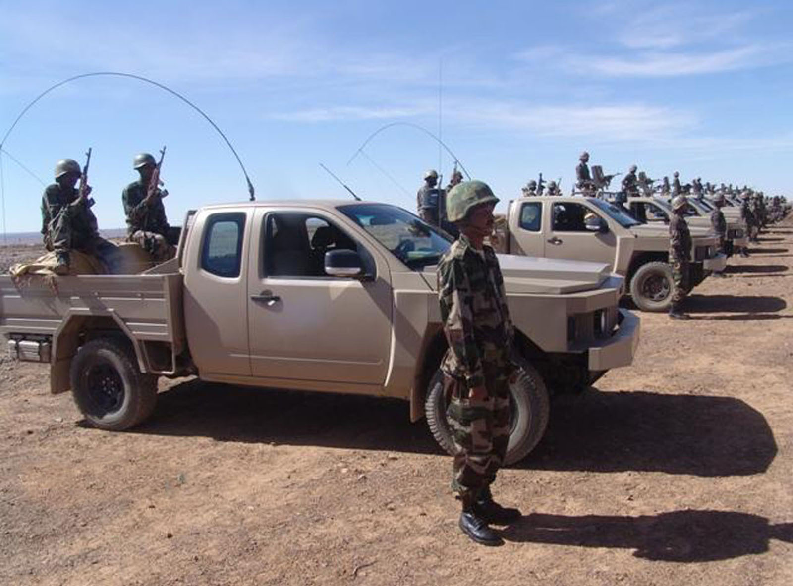 men standing in the back of a truck on the side of a road