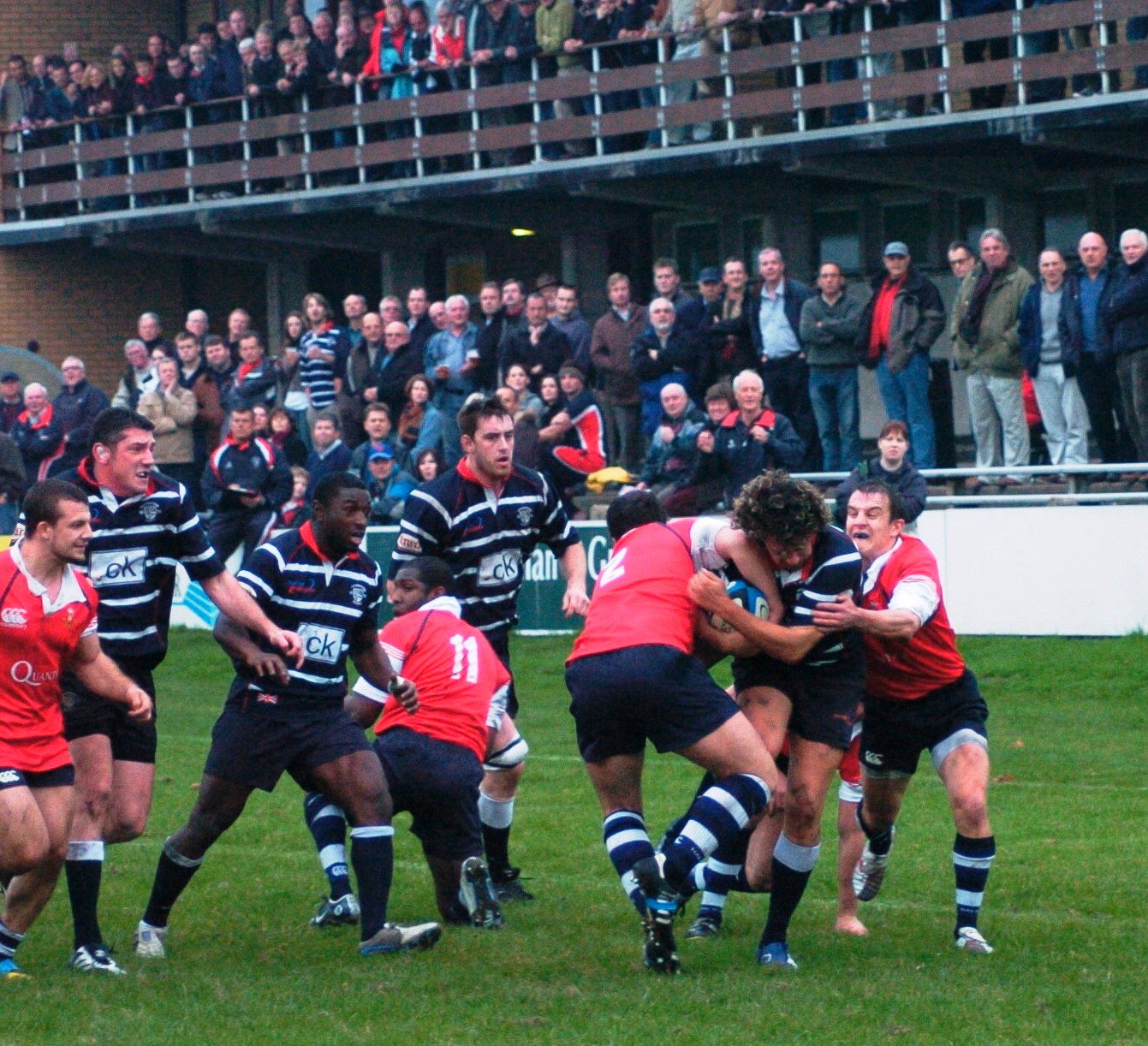 a team of men playing a game of rugby in front of a crowd