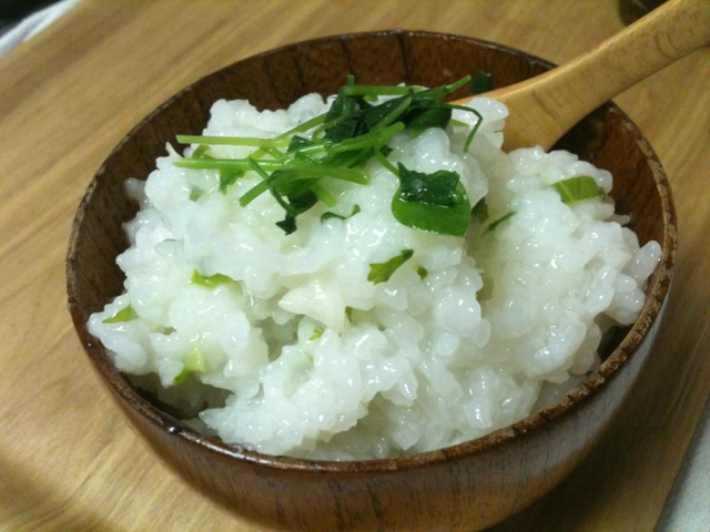 a wooden bowl filled with rice covered in white sauce and garnished with green leaves