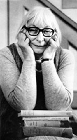 a woman sitting down next to stacks of books and leaning her head on his hands