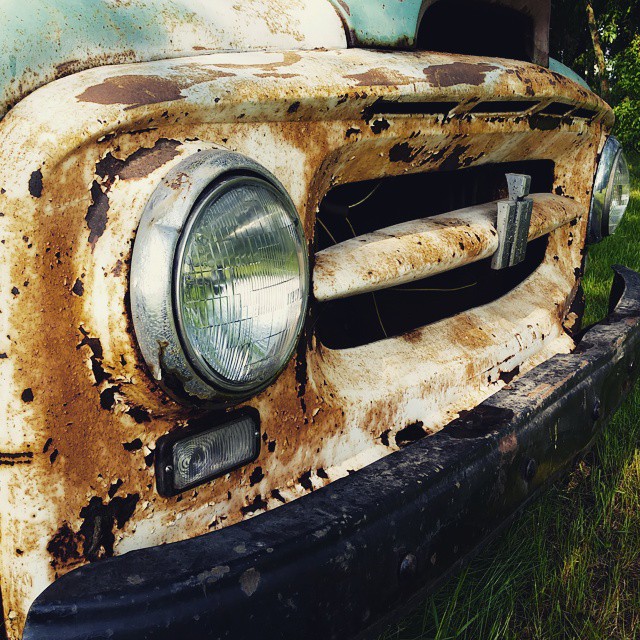 an old rusty old truck sits in the grass