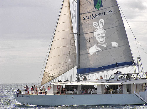 a sail boat with people aboard it and an ad on the back