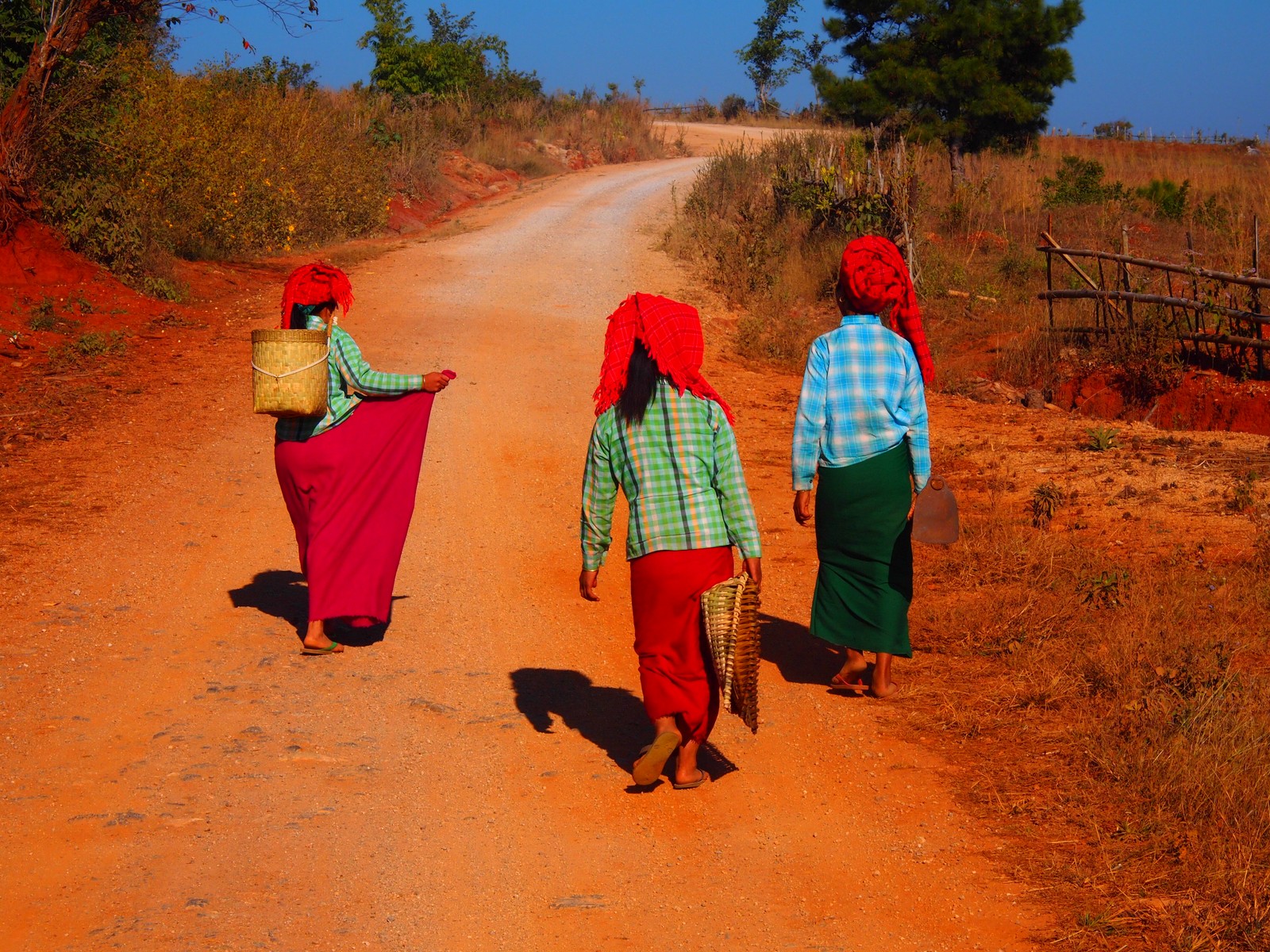 some women in the street walking down a dirt path