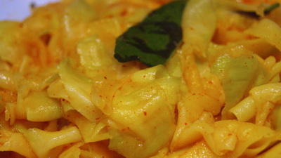 close up of pasta in yellow sauce with greens