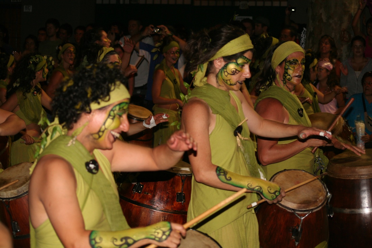 a couple of people in green costumes dancing with a drum