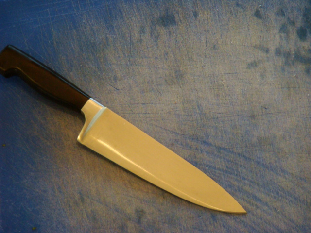 a large yellow knife sitting on top of a blue  board