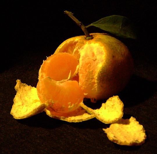 a peeled orange with two pieces cut off sitting on a table