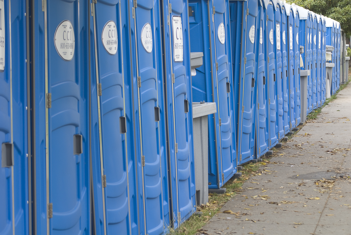 a long row of blue bins lined up along the side of a sidewalk