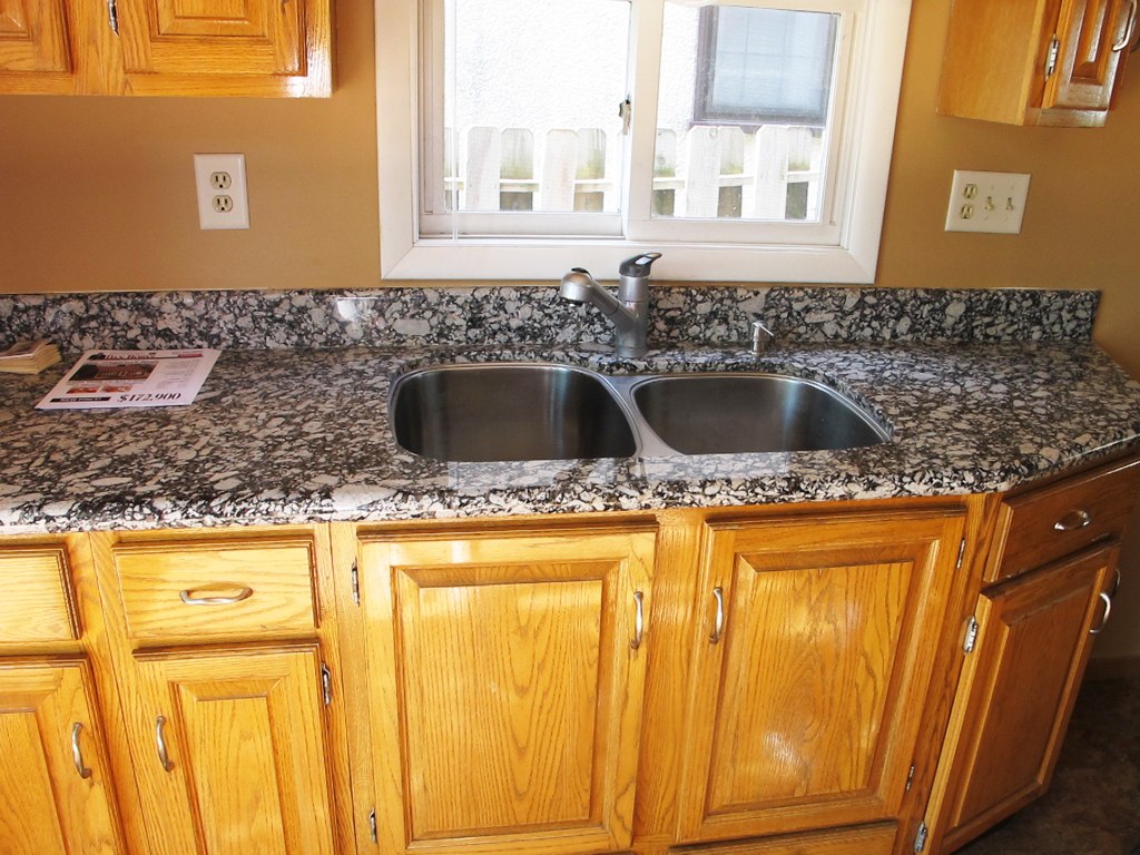 an empty kitchen with double sinks and counter tops