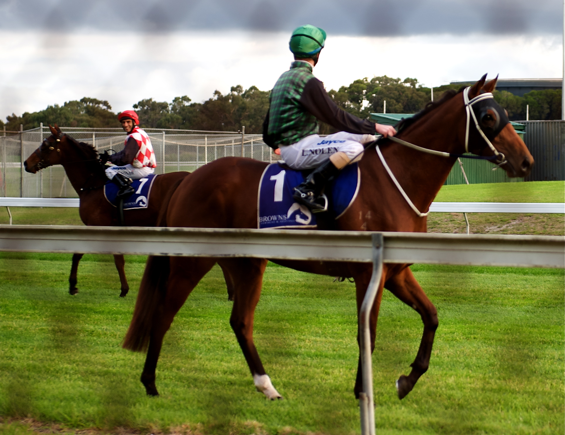 two people wearing jockeys riding on a racing horse