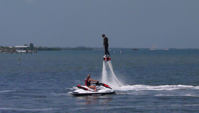 the people is flying over the ocean by jet skis