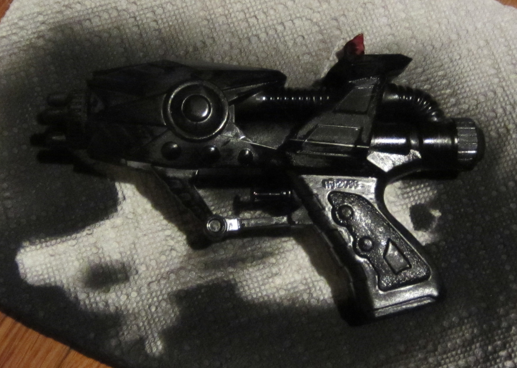 black toy gun with red bullet inside laying on rug