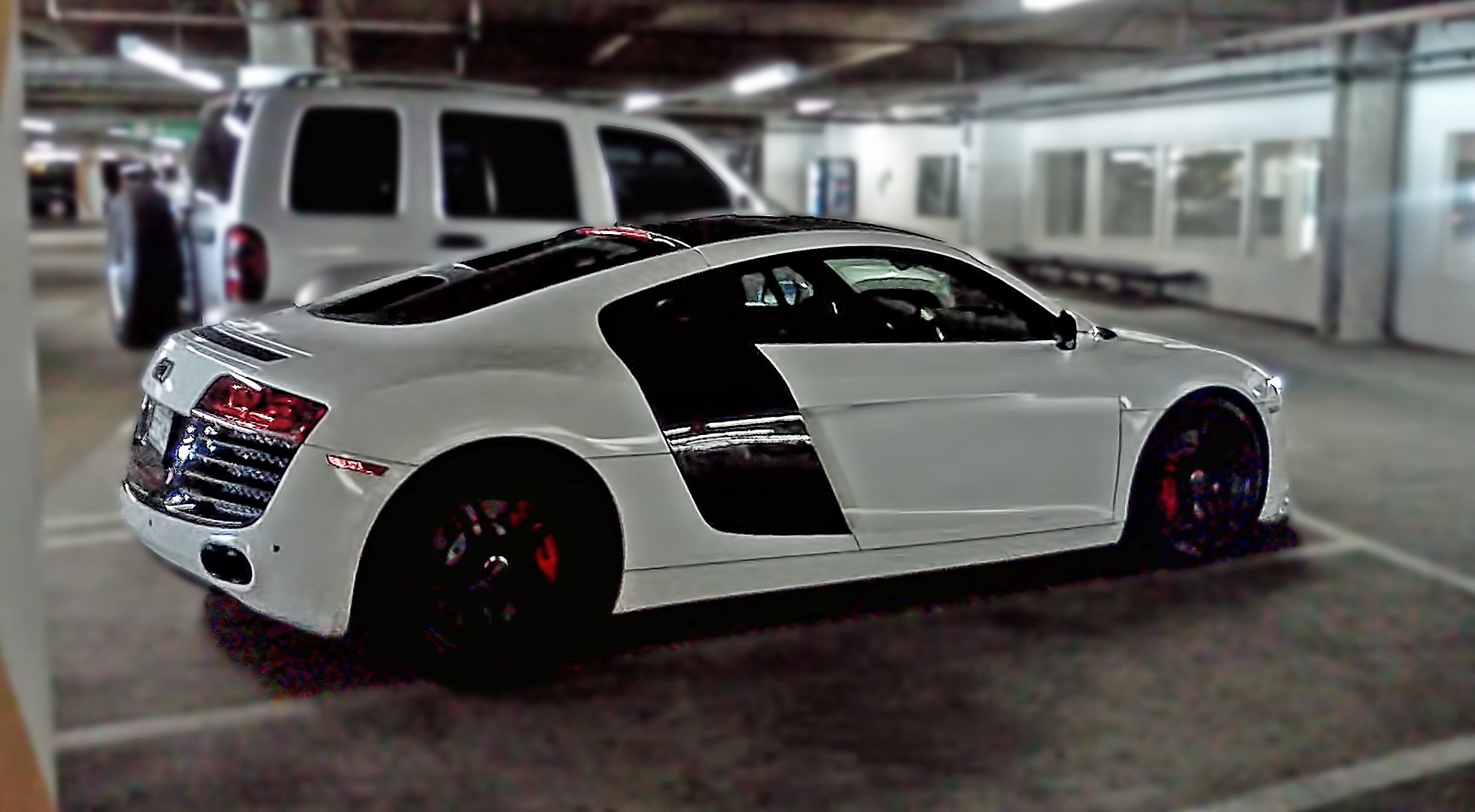 two white cars in a parking garage near other cars