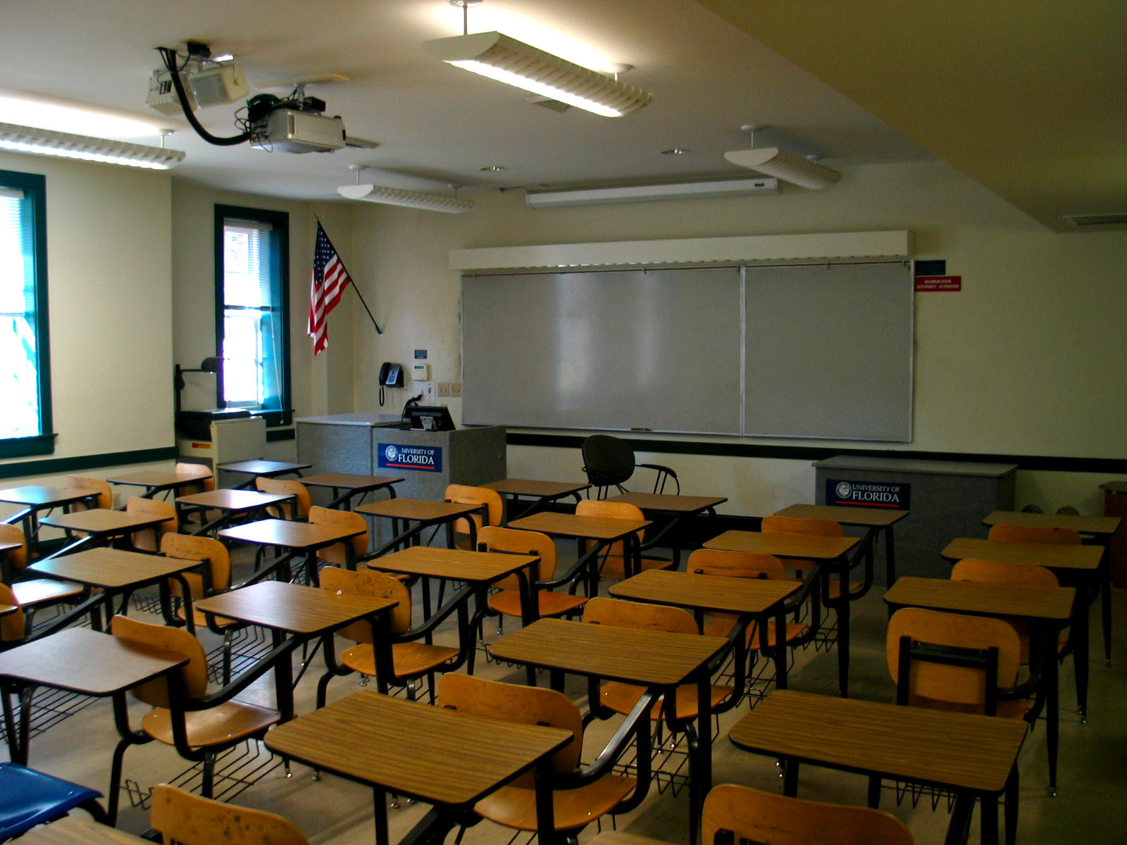 a classroom with lots of wooden chairs and one black board