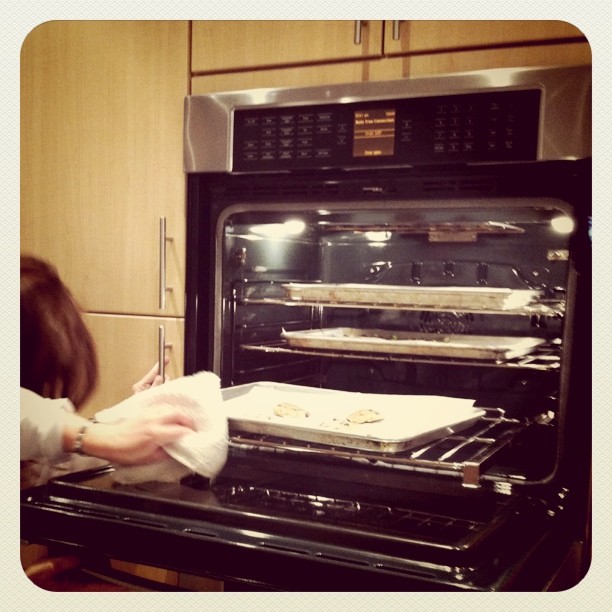 the woman is taking the pan out of the oven