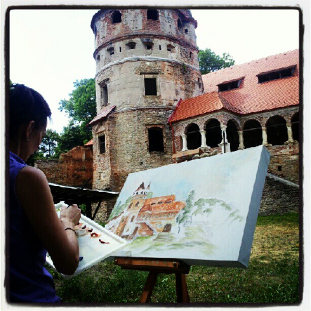 an artistic woman painting in front of a castle like structure