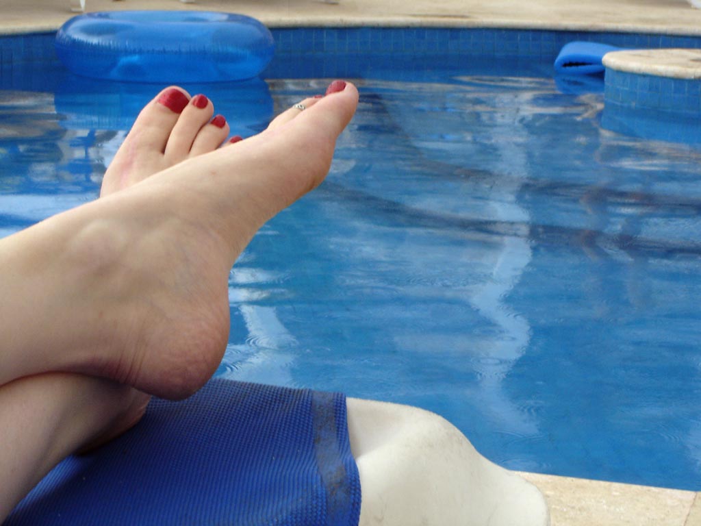 someones feet in the pool with blue and white swimming floats