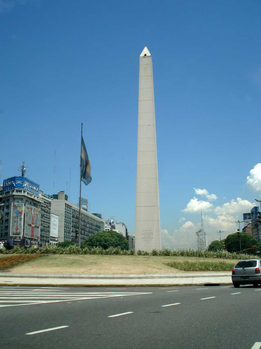 cars are driving past a monument on the road
