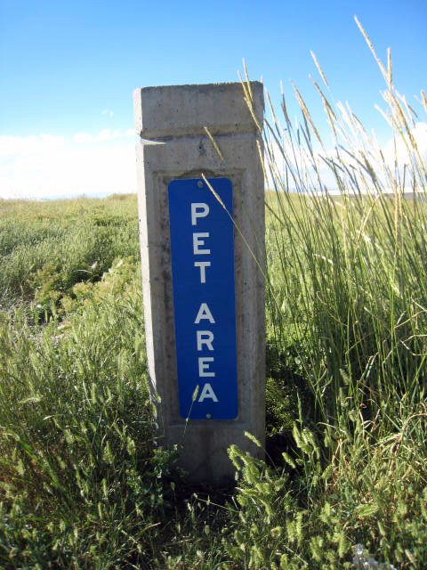 a sign is pictured in the grass near the edge of a field