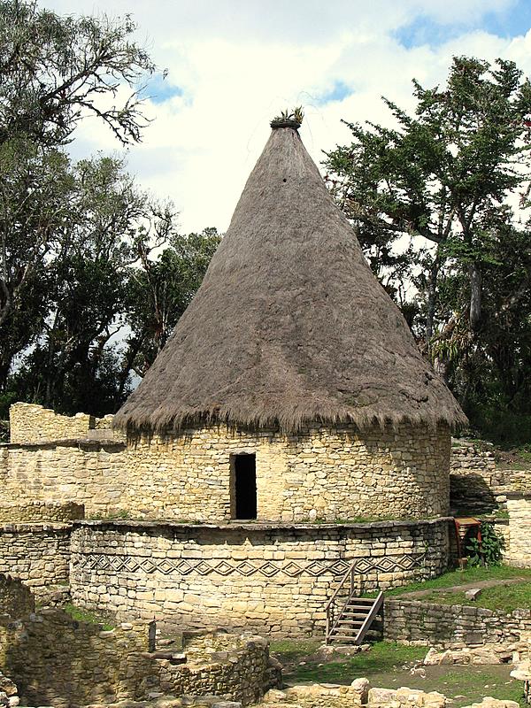 an old adobe style building is next to trees