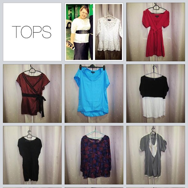 various tops hanging on the wall and a woman standing in front of them