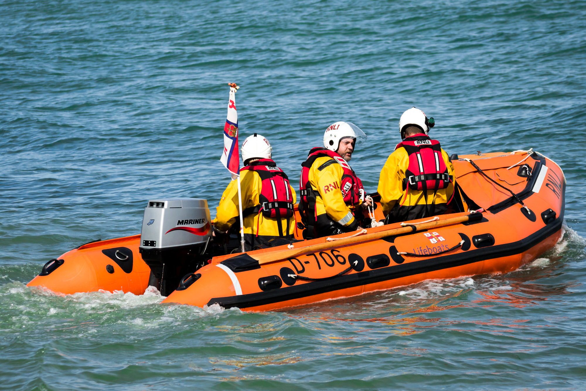 three people in life jackets riding on a raft with a flag