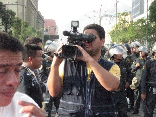 a pographer taking pictures at a crowd of protesters