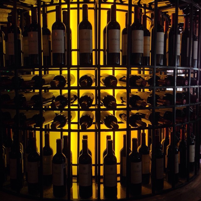 a glass wine rack filled with lots of bottles
