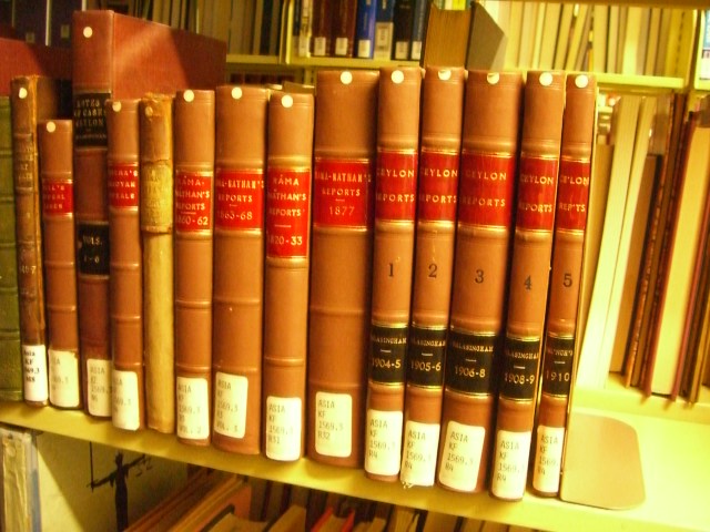 a row of brown books sit on a book shelf