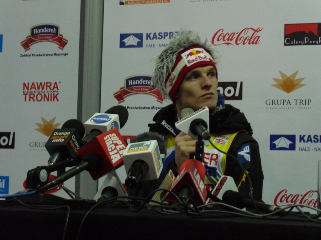 a man in a winter hat talking to microphones