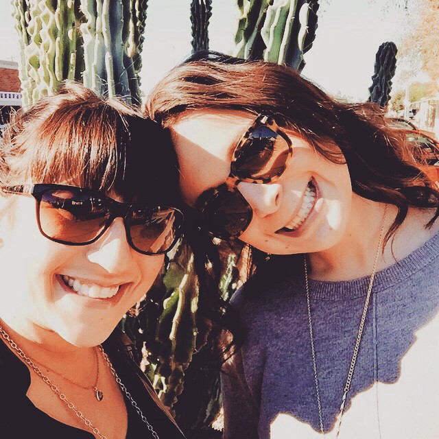 two women smile for the camera beside a cacti