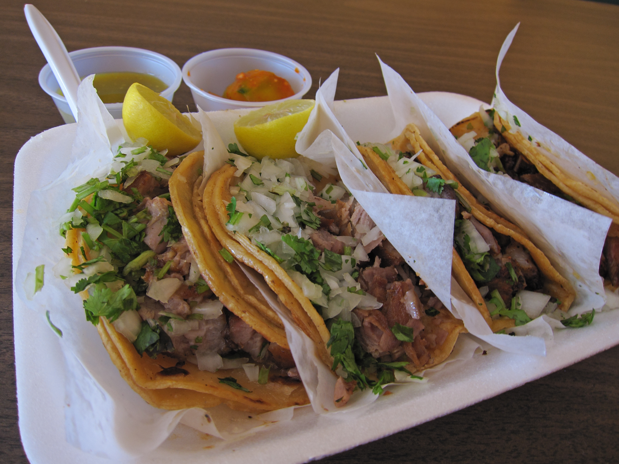 a tray filled with tacos and two sides of some condiments