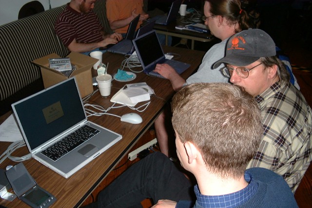 a group of people at a table using lap tops