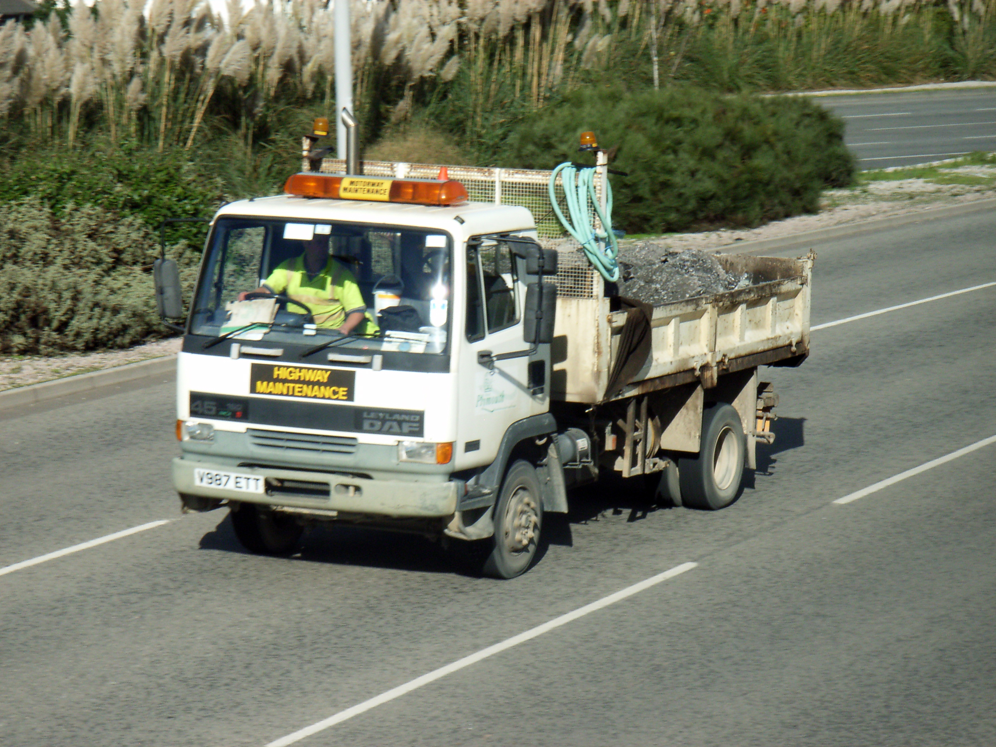 a truck is traveling down the road with a large group of people on it