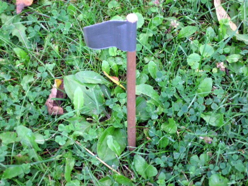 an axe stuck in the green leaves and grass