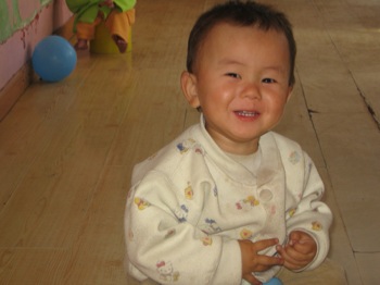 small toddler on the floor smiling for a picture