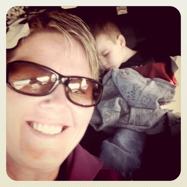 a woman with sunglasses is laying down next to her son