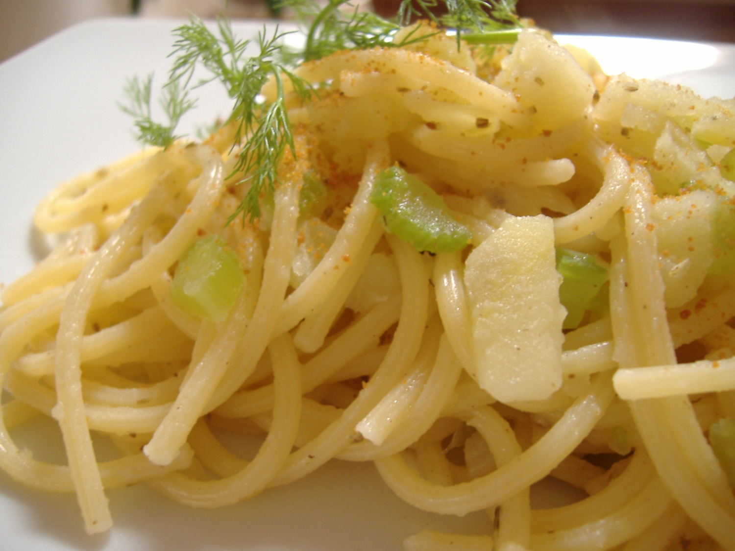 closeup of pasta, on a plate with sprigs of green