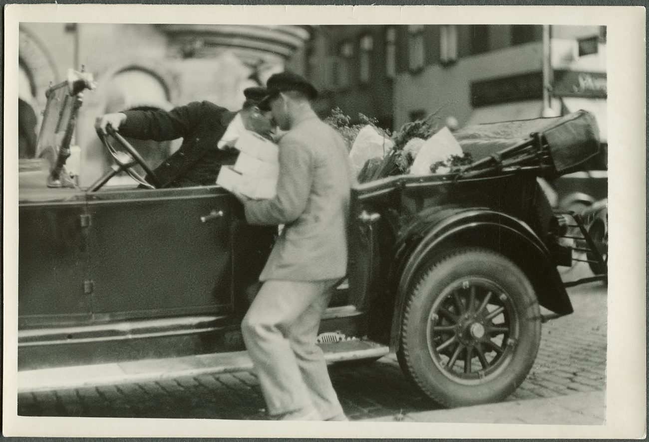 black and white pograph of man leaning on an antique car