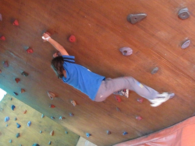 a young man is climbing on the ceiling with red rocks