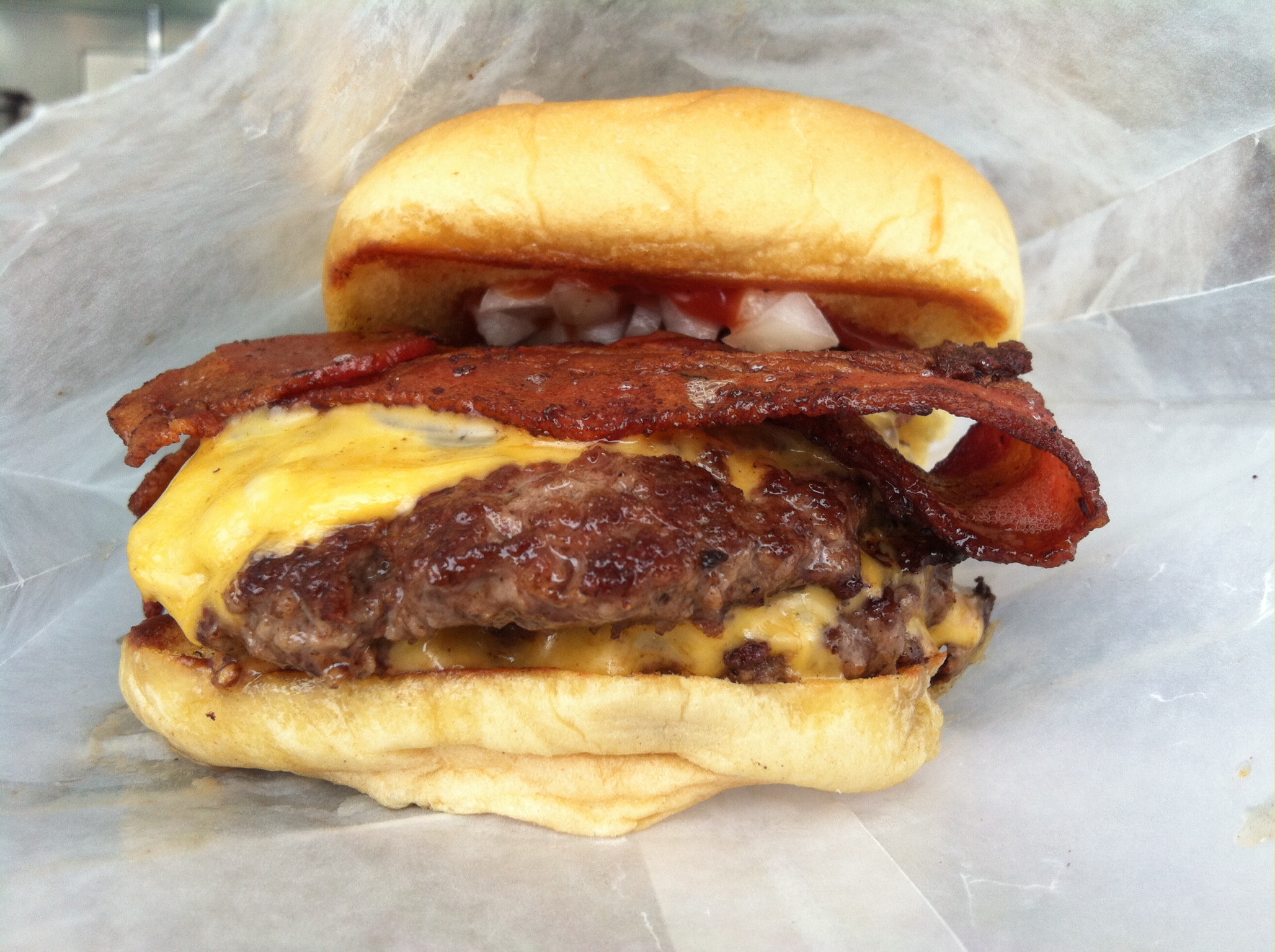 a cheeseburger with bacon sitting in a bun