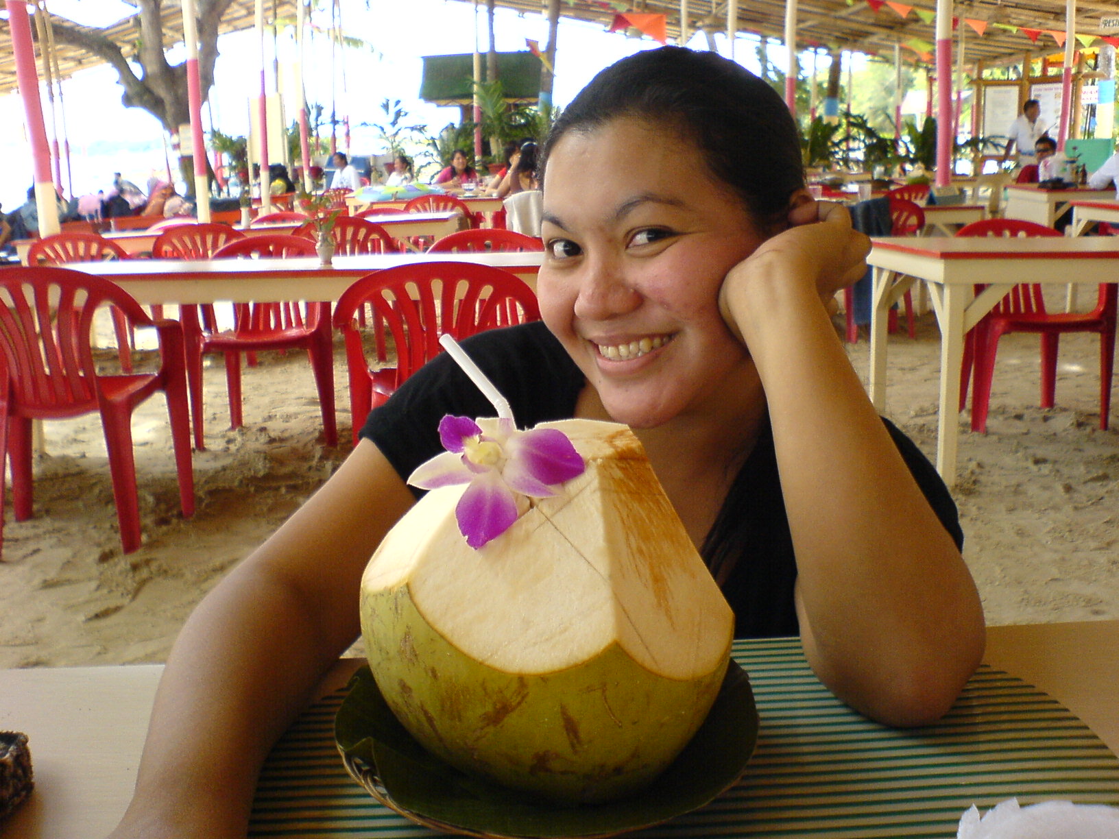 a woman sitting at an outdoor restaurant with a fruit smoothie