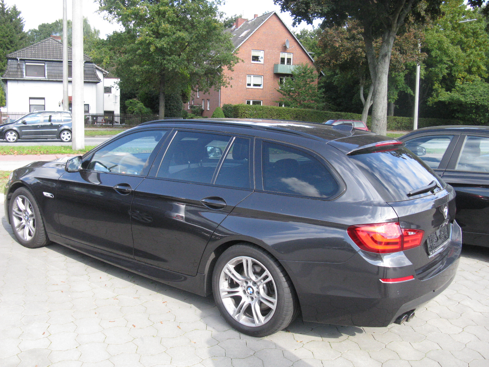 the black bmw car is parked in a driveway