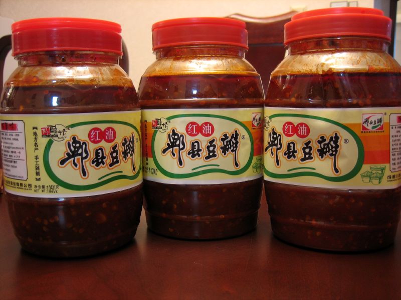 four jars with chili sauce on a table