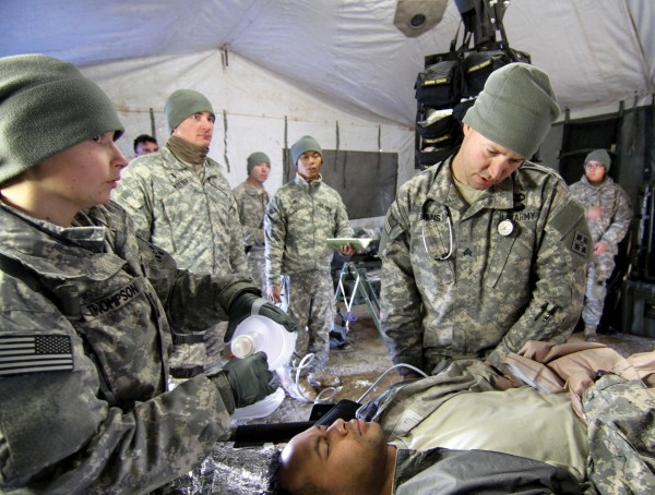 a group of soldiers standing around a person laying on the ground