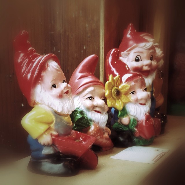 a number of figurines of little garden gnomes on a shelf