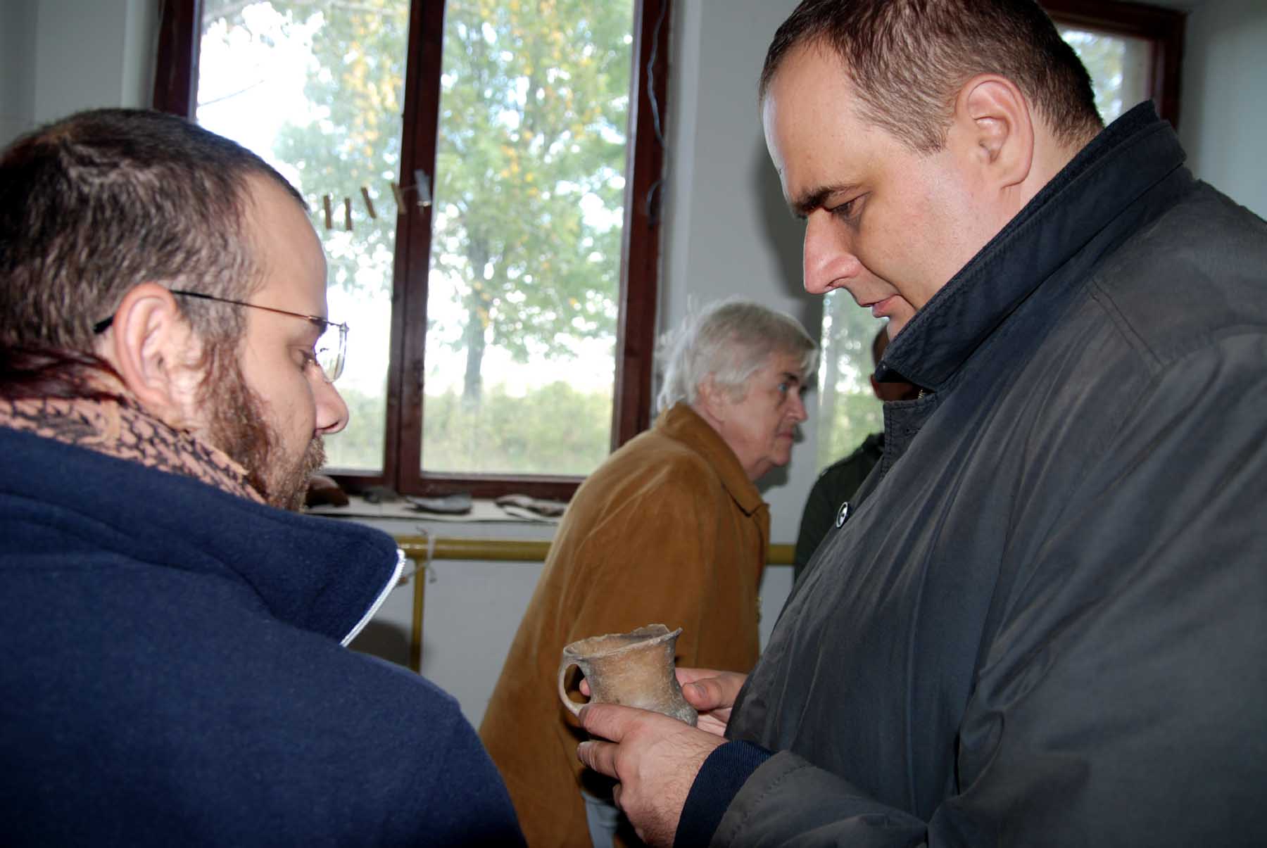 two men standing near each other holding wine glasses