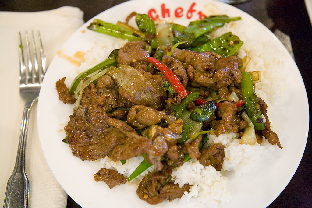 some meat and vegetables on some rice with a fork